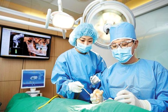강남임플란트수술방법 – 치과 의료진이 환자의 임플란트 수술을 진행하는 모습